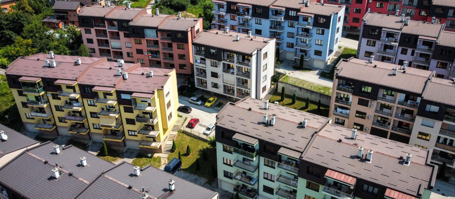 NPL, zavarovani z nepremičninami: zračni pogled na živahen stanovanjski kompleks z večbarvnimi stanovanjskimi stavbami, obdanimi z zelenimi površinami v Bosni in Hercegovini
