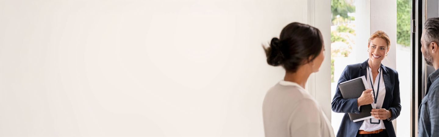 Zaposleni EOS z dokumenti pozdravi par pri vhodnih vratih.