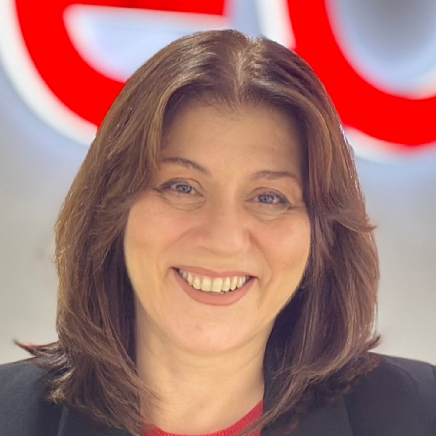 Belén Barreiro, agent kontaktnega centra pri EOS v Španiji, se naslanja na pult v črnem blazerju pred svetlim logotipom EOS.