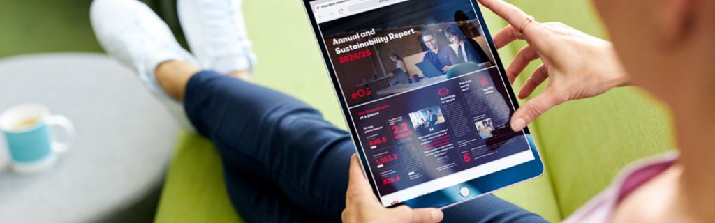 Oseba na zelenem kavču, ki si ogleduje Letno poročilo in Poročilo o trajnostnem razvoju EOS 2024/25 na tablici