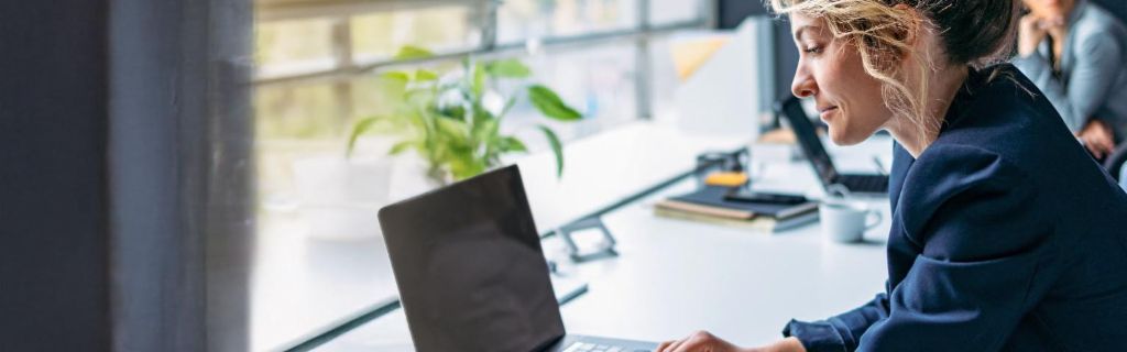 Young woman is working on a laptop in a modern office.