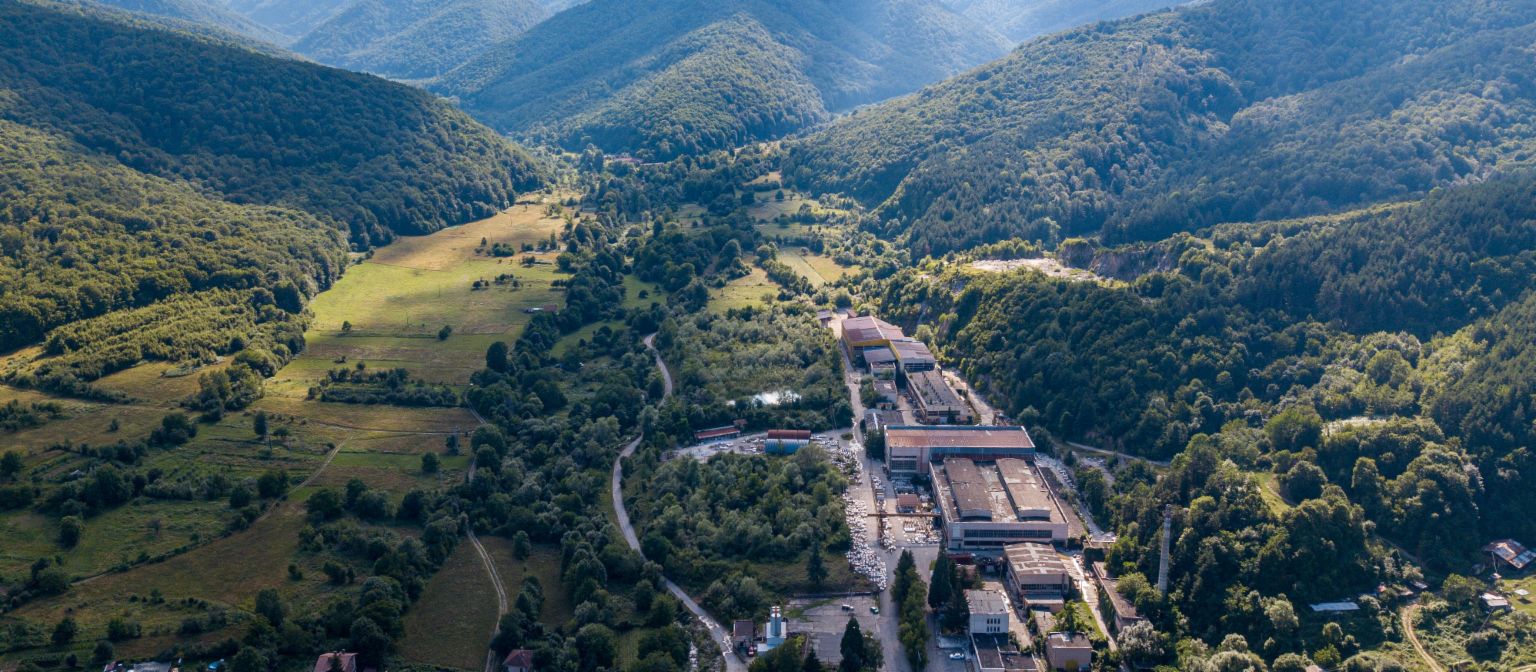 Upravljanje terjatev: Slika prikazuje pogled iz zraka na tovarno marmorja v Berkovici, obkroženo s številnimi drevesi v dolini. Zaradi zavezanosti EOS-a je bilo tradicionalno podjetje ohranjeno.