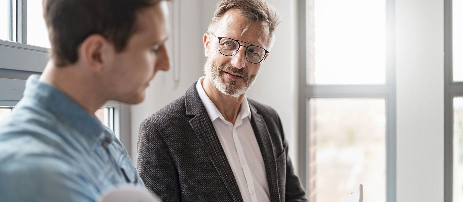 Dva moška v pisarni razpravljata o rezultatih študije skupine EOS Evropske plačilne prakse 2025 o digitalizaciji v upravljanju terjatev.