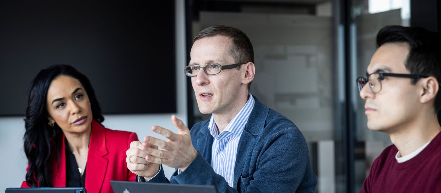 Tri osebe se pogovarjajo v pisarni.