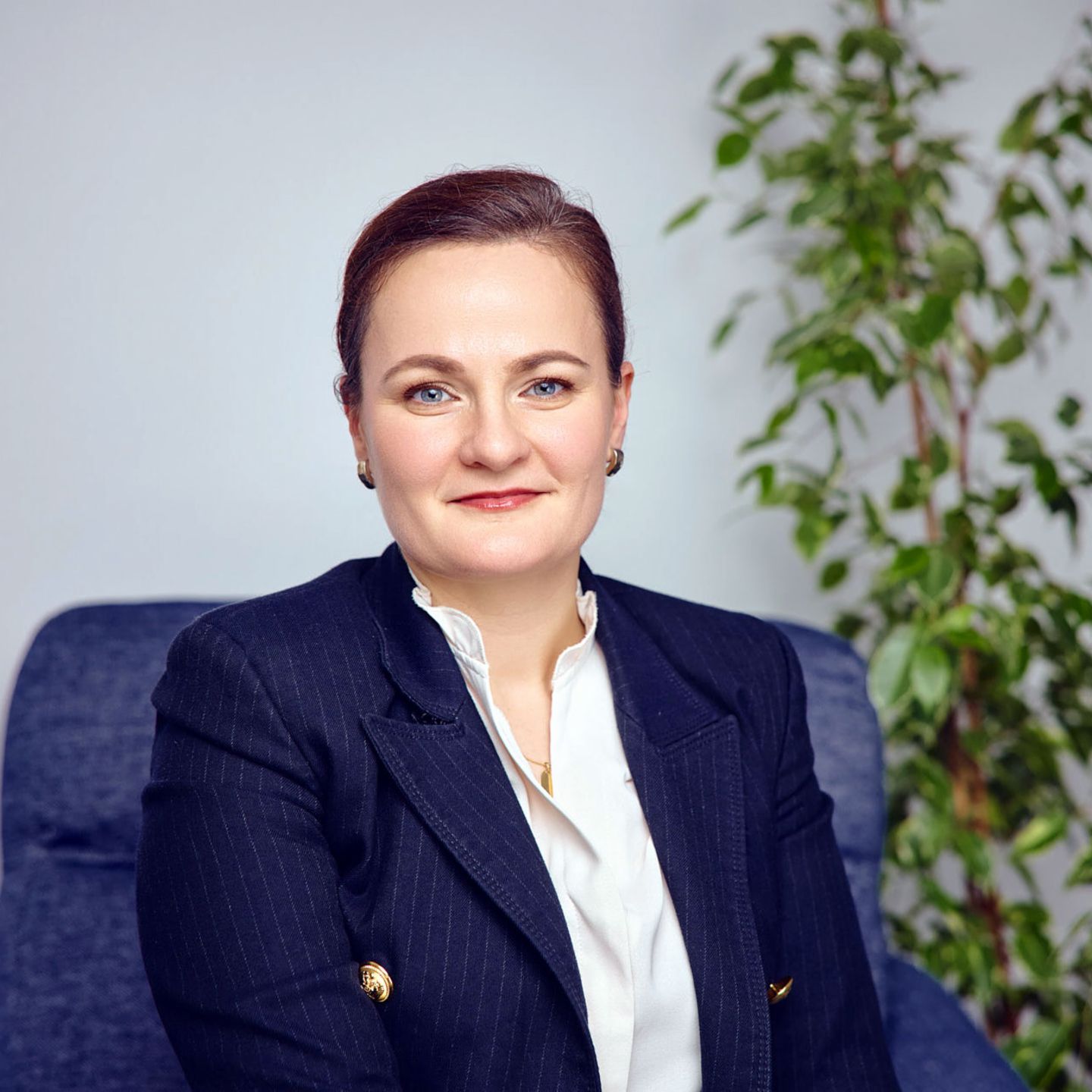 Marina Jozić, HR managerka, sedi na modrem stolu z zeleno rastlino v ozadju, oblečena v temen suknjič in belo bluzo.