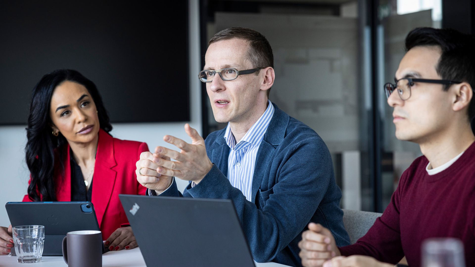 Tri osebe se pogovarjajo v pisarni.